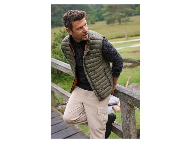 Homme portant un gilet matelassé vert et un pantalon beige.