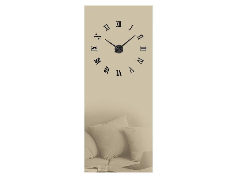 Horloge murale à chiffres romains au-dessus d'un canapé avec coussins et ordinateur portable.