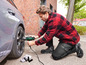 Un homme utilise une visseuse Parkside pour changer une roue de voiture.