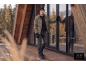 Homme en doudoune olive, jean foncé, bonnet et gants sur une terrasse en bois.