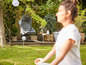 Une femme médite dans un jardin avec un fauteuil suspendu et une table d'appoint.