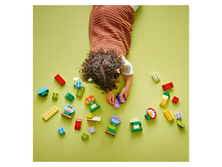 Enfant jouant avec des briques LEGO DUPLO colorées sur fond vert clair