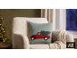 Coussin avec camion de Noël rouge et sapin dans un cadre de Noël douillet.