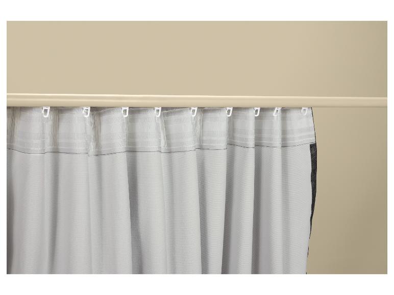 Rideau blanc avec crochets suspendu à une tringle à rideaux beige.