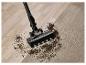 Aspirateur sans fil nettoyant la saleté d'un parquet et d'un tapis.