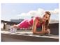 Femme faisant une planche en tenue de sport rose sur un rooftop.