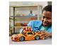 Garçon jouant avec une voiture de course LEGO Technic orange sur une table.