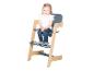 Petite fille assise dans une chaise haute en bois et grise avec un sourire.