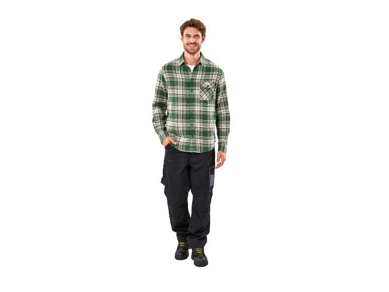 Homme en chemise à carreaux verte et pantalon de travail noir