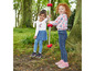 Deux filles jouent avec une corde dans la forêt, l'une porte un jean et un t-shirt rose, l'autre une jupe et un t-shirt blanc.