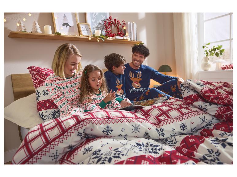 Famille en pyjamas de Noël assortis lisant un livre au lit.