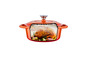 Une cocotte en fonte orange avec un poulet rôti à l'intérieur.