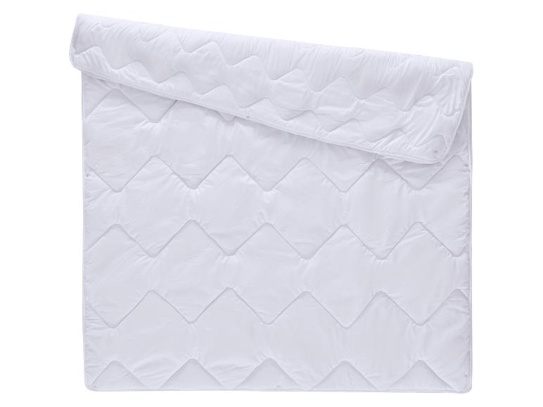 Couette blanche matelassée avec motif ondulé, partiellement pliée.