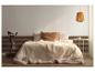 Chambre à coucher avec un lit, une literie claire et une suspension tressée.