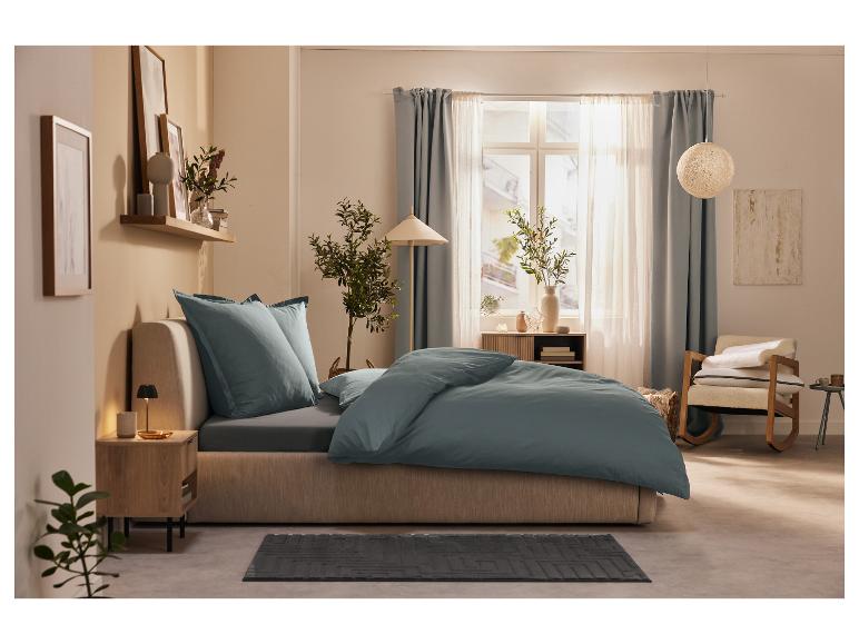 Lit avec draps bleu-gris et décoration minimaliste.