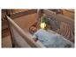 Bébé dormant dans un lit parapluie avec une veilleuse crocodile lumineuse.