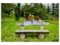 Banc en bois avec jardinières de fleurs dans un jardin verdoyant.
