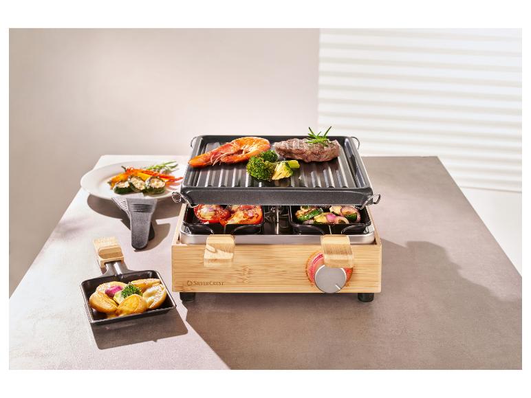 Un appareil à raclette en bambou avec de la viande, des crevettes et des légumes sur le grill et dans les poêlons.