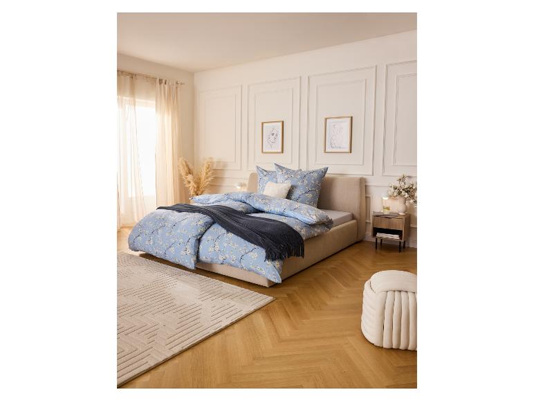 Chambre avec lit, table de chevet LIVARNO®, tapis et pouf aux couleurs claires.