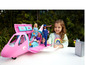 Une fille joue avec un avion rose Barbie et des poupées.