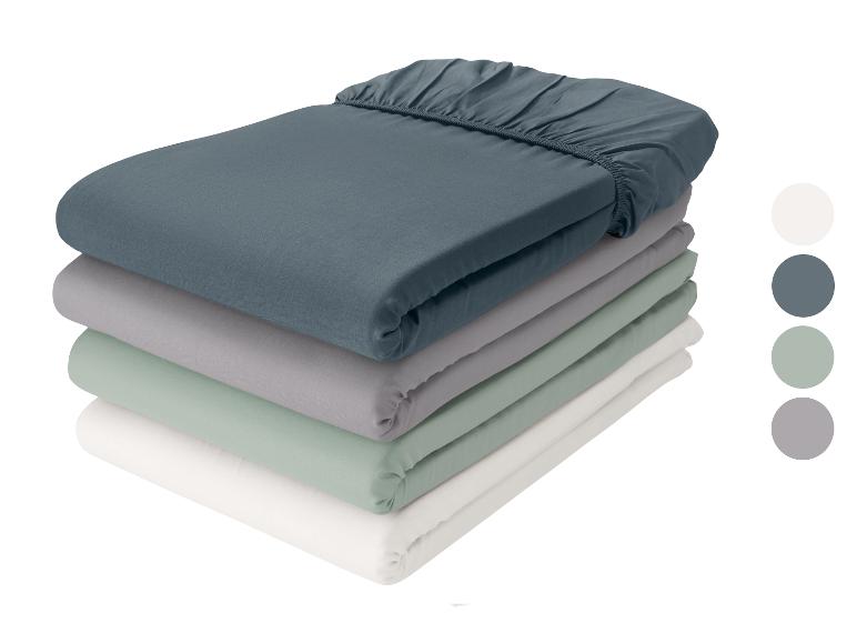 Pile de quatre draps-housses en bleu foncé, gris, vert clair et blanc, avec des échantillons de couleurs.