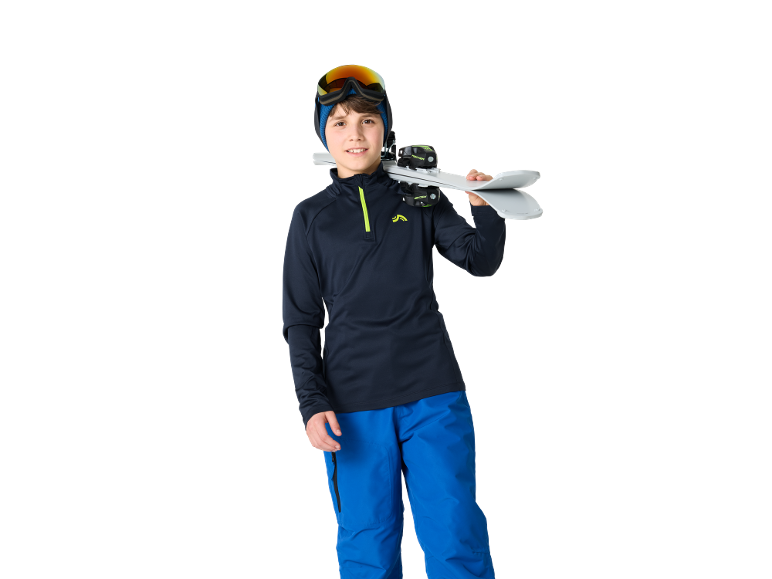 Garçon en tenue de ski avec des skis sur l'épaule, prêt pour les sports d'hiver.
