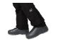 Pantalon noir avec logo blanc et chaussures noires à semelle grise.