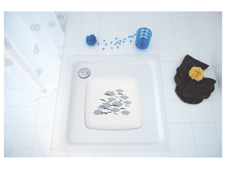 Tapis de bain avec imprimé nuages et oiseaux dans une cabine de douche blanche.