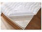 Un protège-matelas blanc à motif ondulé sur un matelas à motif quadrillé.