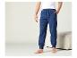 Un homme portant un pantalon de survêtement bleu et un t-shirt blanc.