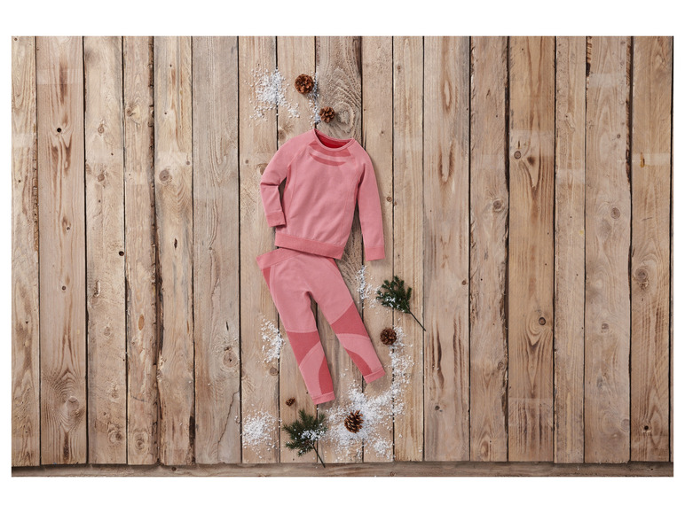 Un survêtement rose à manches longues et leggings sur un fond en bois