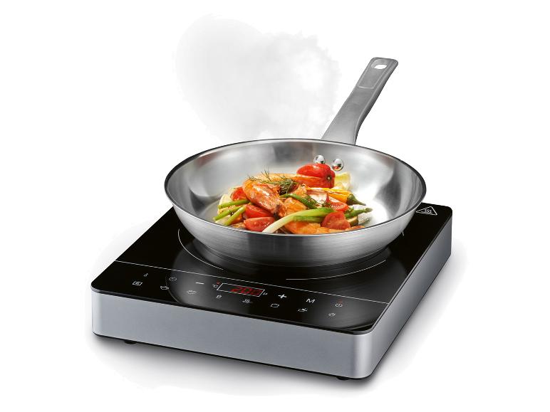 Plaque de cuisson électrique avec une poêle et des crevettes sautées.