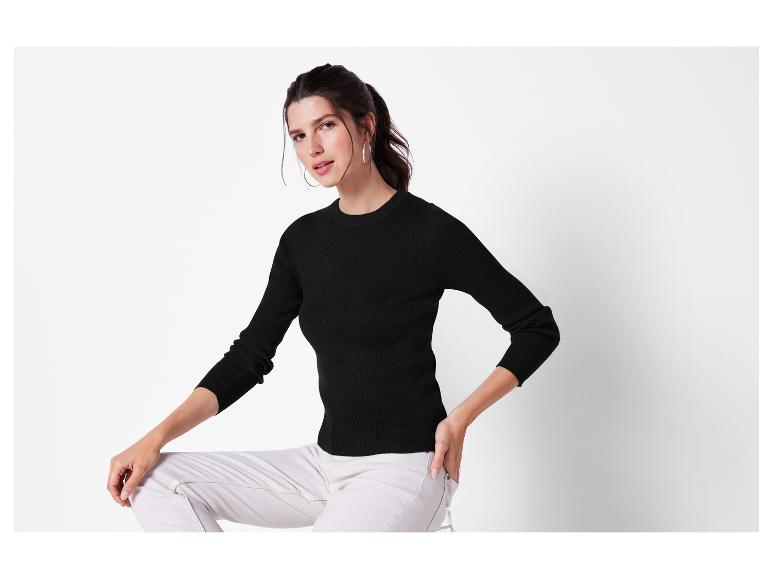 Une femme portant un pull noir et un pantalon blanc.