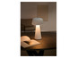 Une lampe de table blanche en forme de champignon sur une table en bois avec un livre.