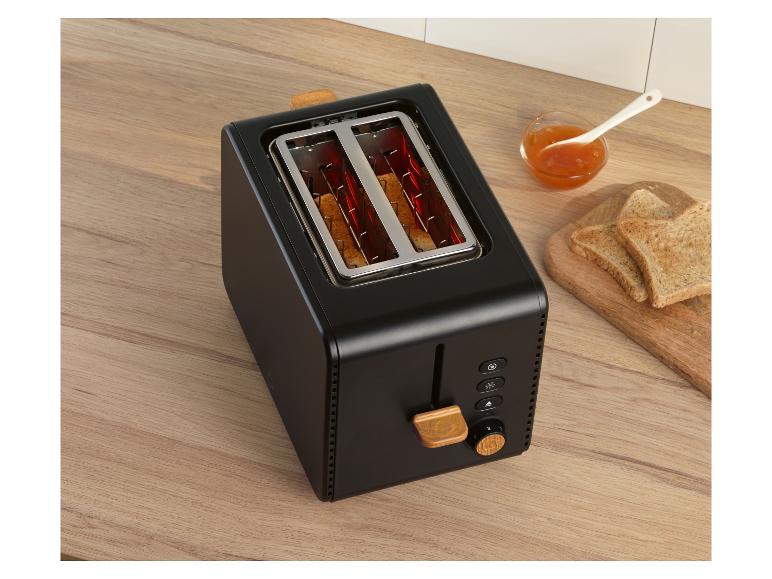 Grille-pain noir avec détails en bois, toasts et confiture sur une table en bois.