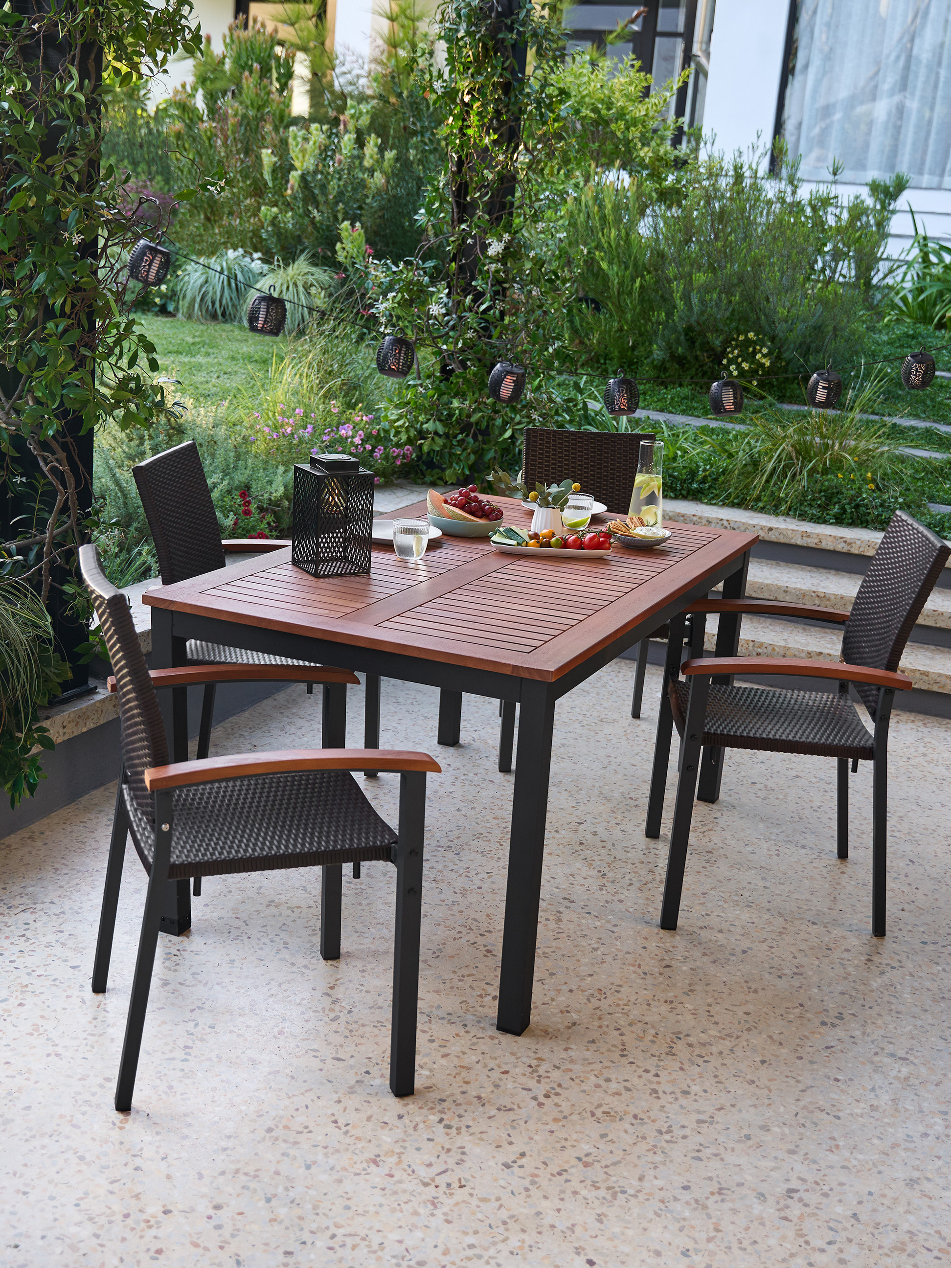 Table de jardin en bois avec chaises et décorations sur une terrasse.
