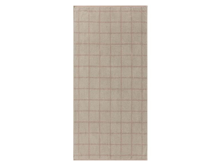 Serviette de bain beige à carreaux rose pâle.