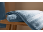 Serviettes en éponge bleues pliées sur un tabouret en bois.