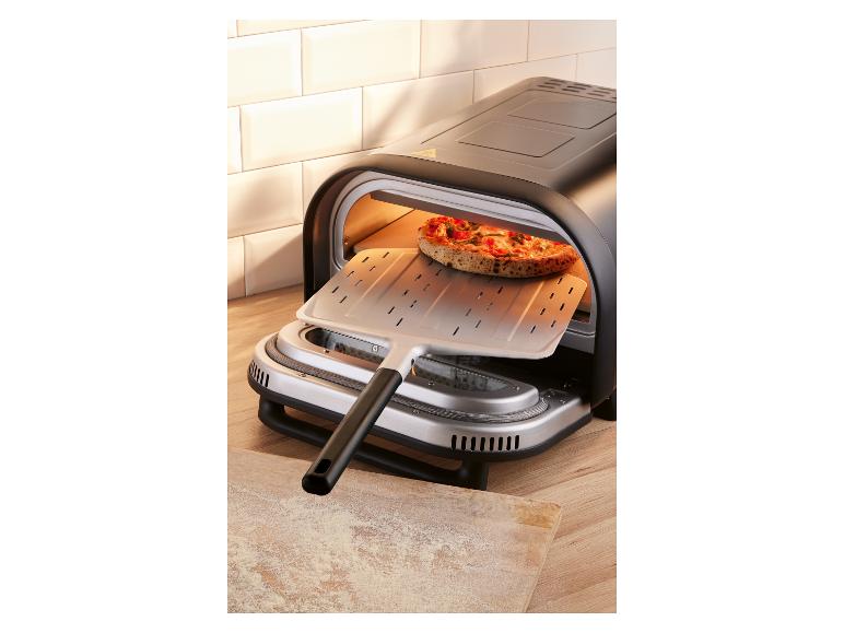 Four à pizza électrique avec une pizza sur le point d'être insérée avec une pelle.