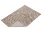 Tapis de bain beige avec une texture bouclée et un bord relevé.