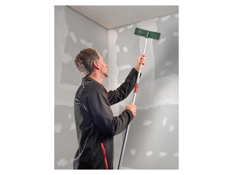 Homme ponçant un mur avec une ponceuse à long manche.
