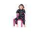 Un enfant souriant dans une combinaison de Noël bleu foncé assis sur une chaise rose