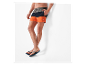 Un homme portant un short de bain tricolore et des tongs.