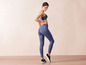 Une femme portant un soutien-gorge de sport bleu et un legging à motif abstrait.
