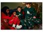 Des enfants en pyjamas de Noël avec des motifs de rennes et d'arbres de Noël.