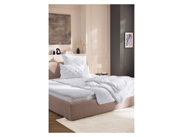Literie et couettes blanches dans une chambre beige avec art et tables de chevet.