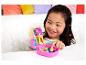 Fille sourit et joue avec un jouet Polly Pocket rose ouvert.