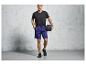 Homme portant un t-shirt noir et un short bleu tenant un ballon de médecine.