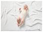 Un bébé dans un body blanc sur une couverture blanche en tricot.