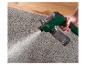Un vaporisateur Parkside vert pulvérise de l'eau sur un tapis gris.